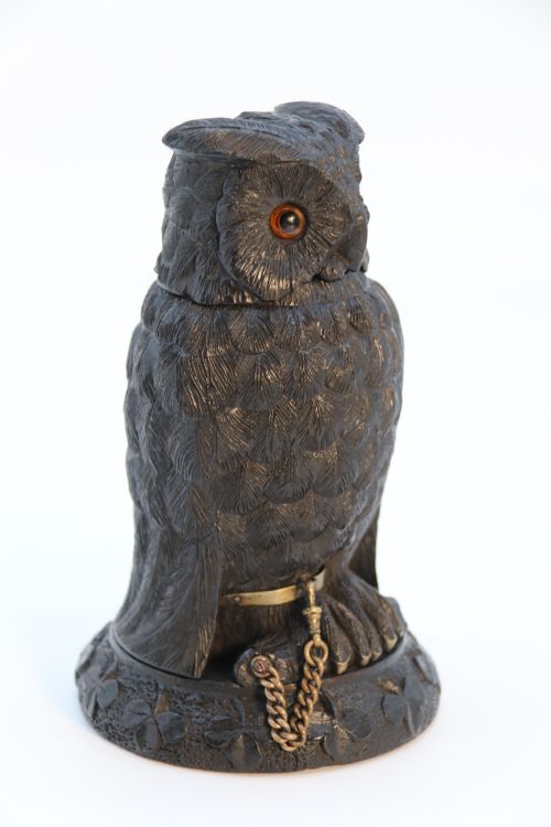 fig 1. A hand-carved dark oak inkstand crafted in the likeness of an owl with glass eyes and a brass tether, resting on a carved base with shamrock details.