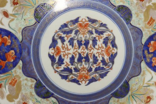fig 1. A circular hand-painted Japanese Imari porcelain charger featuring cobalt blue, iron red, and gilt decorative panels depicting birds, goldfish, and botanical motifs.