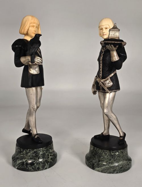 fig 2. A pair of Art Deco chryselephantine statuettes depicting medieval page boys in silvered and dark bronze with carved ivory heads on green marble bases.