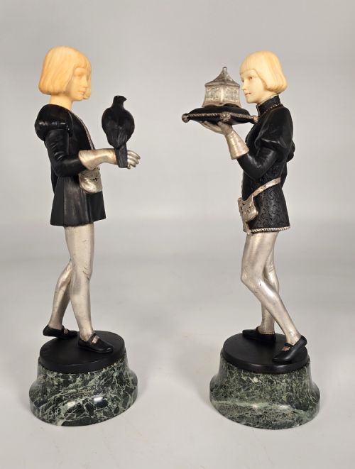 fig 3. A pair of Art Deco chryselephantine statuettes depicting medieval page boys in silvered and dark bronze with carved ivory heads on green marble bases.