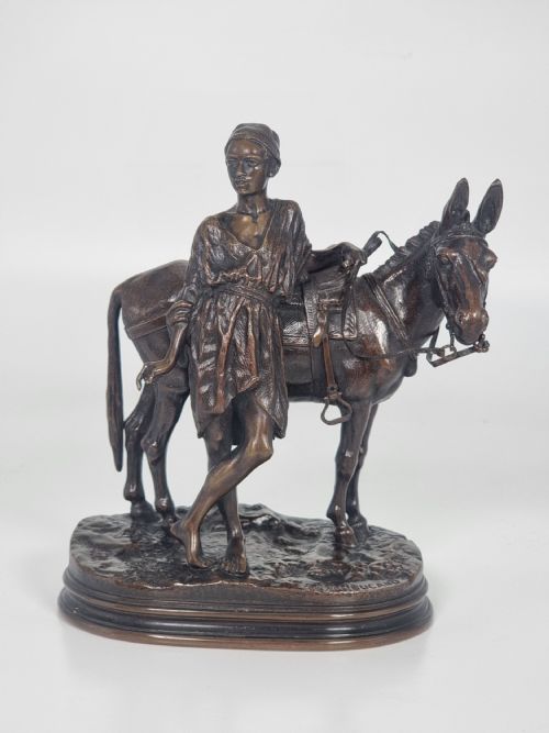 fig 1. A patinated bronze sculpture depicting an Egyptian man leaning against a saddled donkey on an oval base.