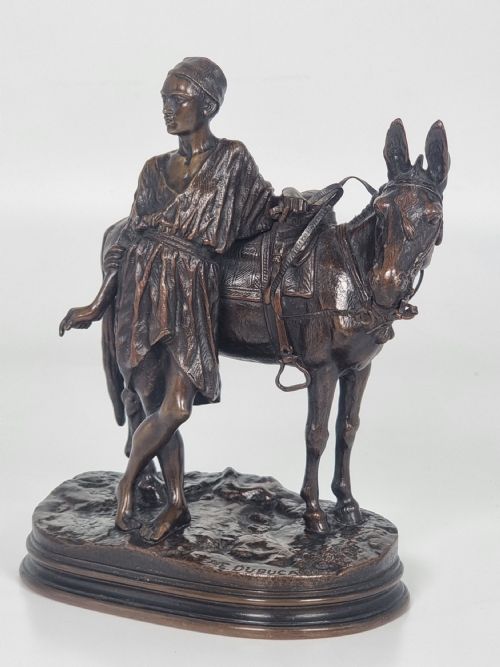 fig 2. A patinated bronze sculpture depicting an Egyptian man leaning against a saddled donkey on an oval base.