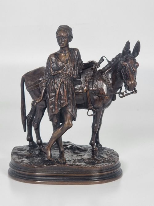 fig 3. A patinated bronze sculpture depicting an Egyptian man leaning against a saddled donkey on an oval base.