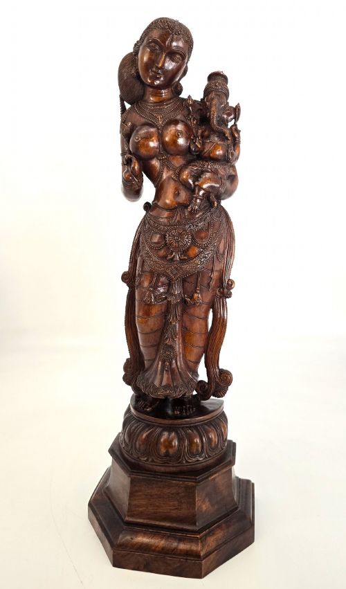 fig 1. A hand-carved dark wood statue depicting the Goddess Parvati holding infant Ganesha, mounted on an octagonal wooden base.