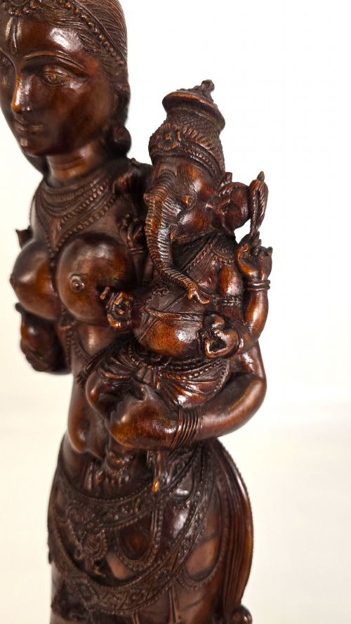 fig 2. A hand-carved dark wood statue depicting the Goddess Parvati holding infant Ganesha, mounted on an octagonal wooden base.