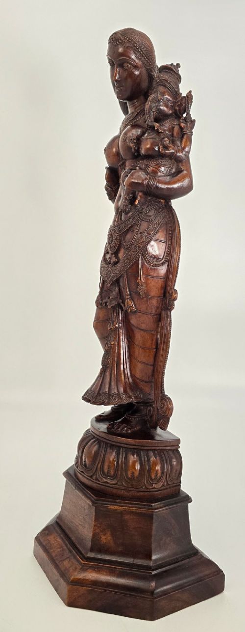 A hand-carved dark wood statue depicting the Goddess Parvati holding infant Ganesha, mounted on an octagonal wooden base. View XIV