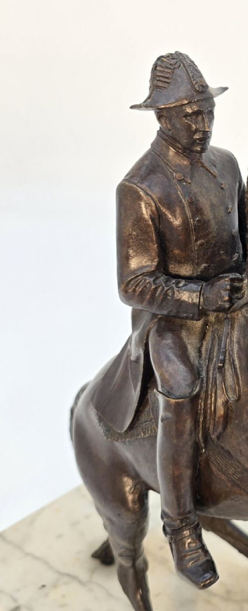 A dark bronze equestrian sculpture depicting a uniformed rider atop a rearing horse, mounted on a rectangular cream marble plinth. View IX