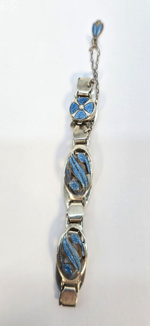fig 1. An Edwardian silver link bracelet featuring pierced oval panels filled with light blue enamel and connected by a safety chain.