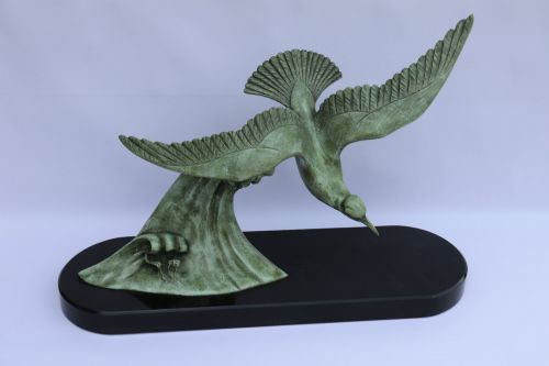 fig 1. A patinated green bronze sculpture depicting an albatross with extended wings skimming a crested wave, mounted on an oval black marble plinth.