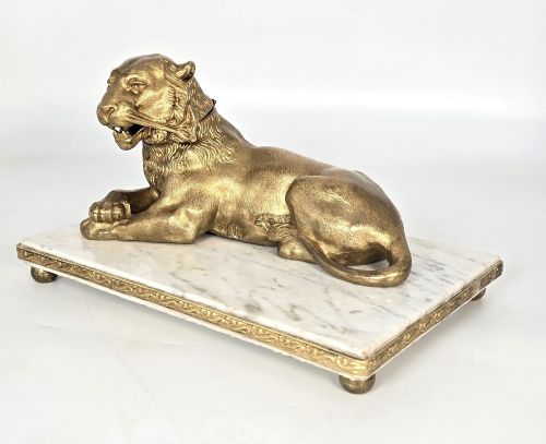 fig 2. A French gilt bronze figure of a recumbent lion mounted on a rectangular white marble plinth with gilt borders and ball feet.