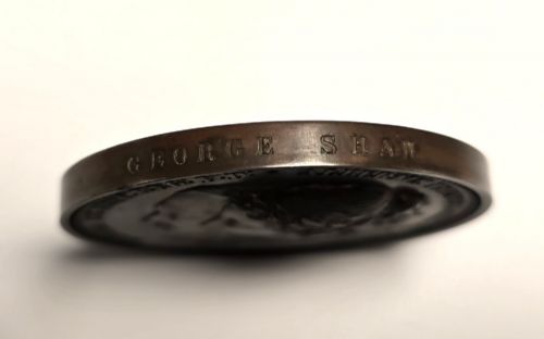 fig 3. A circular dark bronze Victorian medal displaying jugate profile portraits of Queen Victoria and Prince Albert surrounded by Latin text.