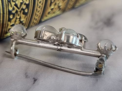 fig 1. An antique silver bar brooch featuring a central flower cluster of oval cabochon moonstones flanked by single moonstones on either side.