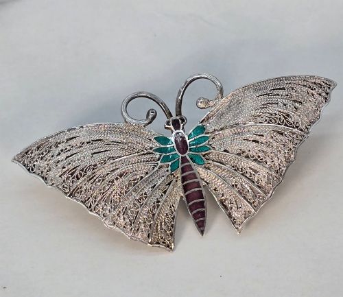 fig 1. A silver filigree butterfly brooch featuring teal and purple enamelled body details.