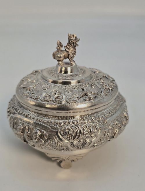fig 1. A circular Anglo-Indian chased silver jar featuring ornate scrollwork detailing and a small animal finial on the lid.