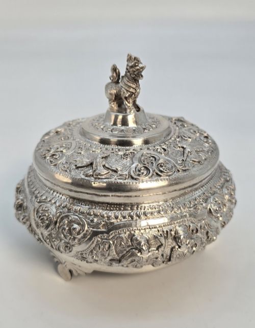 fig 2. A circular Anglo-Indian chased silver jar featuring ornate scrollwork detailing and a small animal finial on the lid.