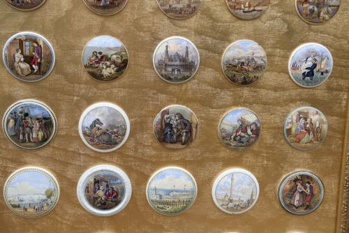 fig 3. A large rectangular ornate gilt frame displaying thirty-five circular Victorian polychrome transfer-printed ceramic pot lids mounted in grid formation.