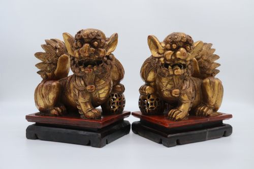 fig 4. A pair of hand-carved Chinese wooden guardian lions finished in gold gilding and red lacquer, seated on dark rectangular bases.