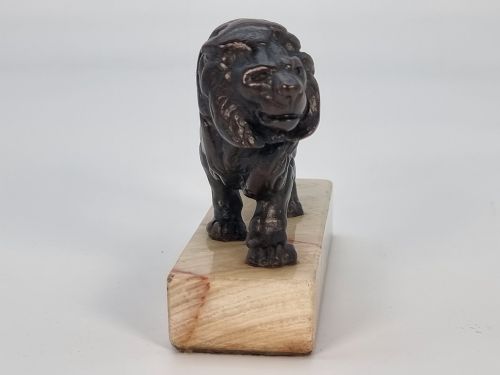 fig 2. A dark patinated bronze sculpture of a prowling lion mounted on a rectangular cream veined onyx base.
