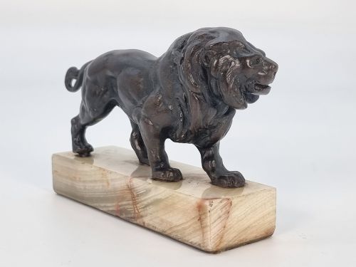 fig 3. A dark patinated bronze sculpture of a prowling lion mounted on a rectangular cream veined onyx base.