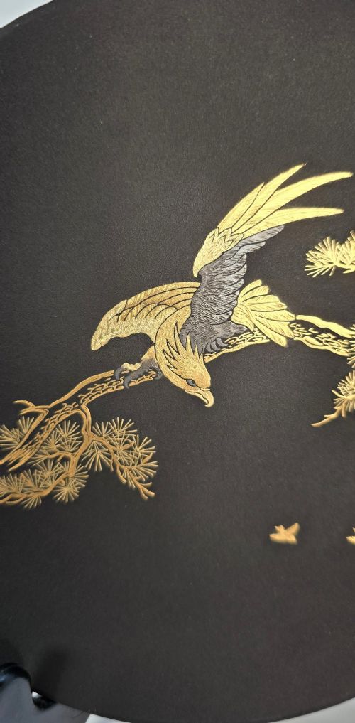A circular black patinated iron plaque featuring an inlaid gold and silver depiction of an eagle perched on a pine branch. View VI