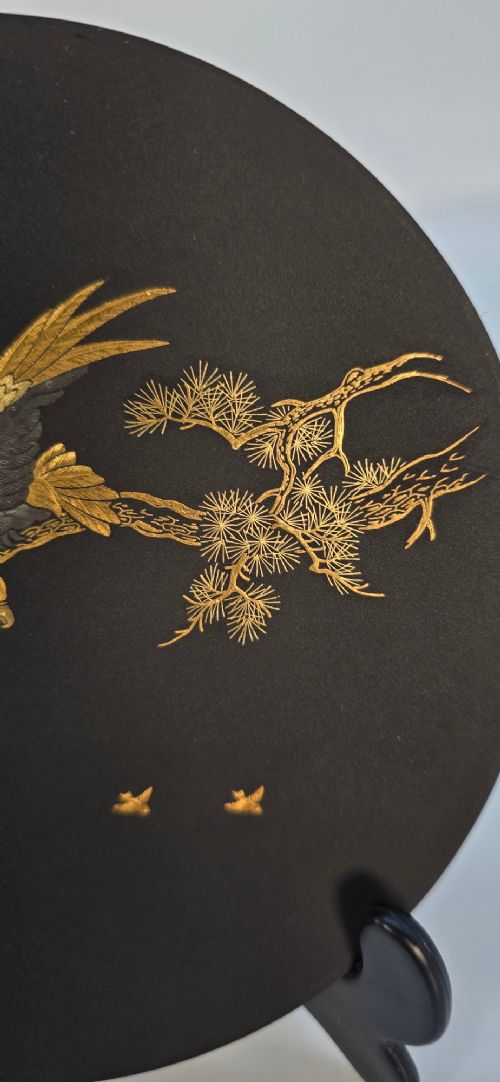 A circular black patinated iron plaque featuring an inlaid gold and silver depiction of an eagle perched on a pine branch. View VII