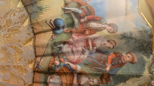 fig 1. A late 18th-century Italian folding fan featuring a hand-painted pastoral scene mounted on carved mother-of-pearl sticks, presented inside a fan-shaped black frame with a cream silk lining.