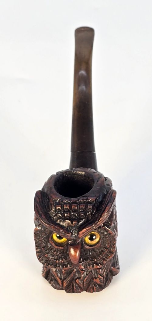 A detailed hand-carved briar wood tobacco pipe crafted in the shape of an owls head featuring yellow glass eyes and a curved black stem. View VI