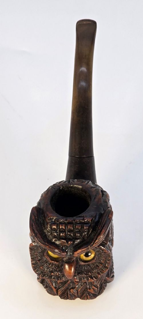 A detailed hand-carved briar wood tobacco pipe crafted in the shape of an owls head featuring yellow glass eyes and a curved black stem. View VII