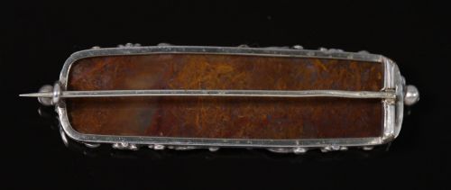 fig 1. An elongated Georgian silver bar brooch featuring a rectangular polished moss agate panel with a scrollwork silver border.
