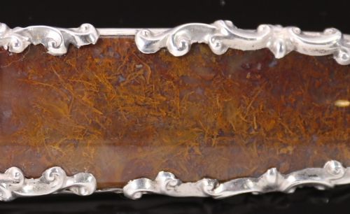fig 2. An elongated Georgian silver bar brooch featuring a rectangular polished moss agate panel with a scrollwork silver border.