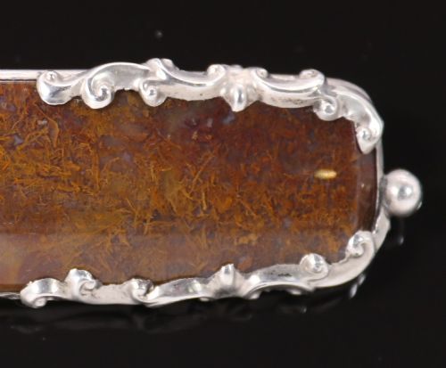 fig 3. An elongated Georgian silver bar brooch featuring a rectangular polished moss agate panel with a scrollwork silver border.