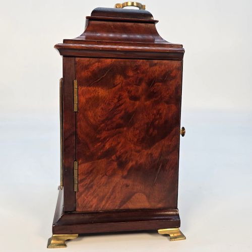 fig 3. A miniature George II style wooden bracket clock featuring a caddy top with brass handle, engraved silvered dial with Roman numerals, and brass feet.