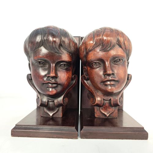fig 3. A pair of carved mahogany bookends depicting the profile busts of choir boys mounted on L-shaped wooden bases.