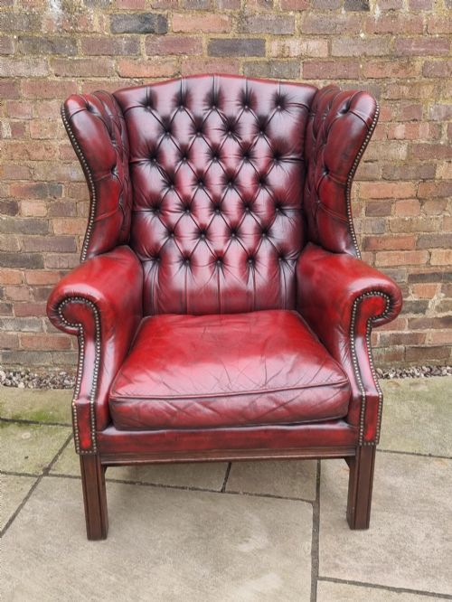 fig 3. A George III style wingback armchair upholstered in deep buttoned burgundy red leather with brass stud detailing and square mahogany legs.