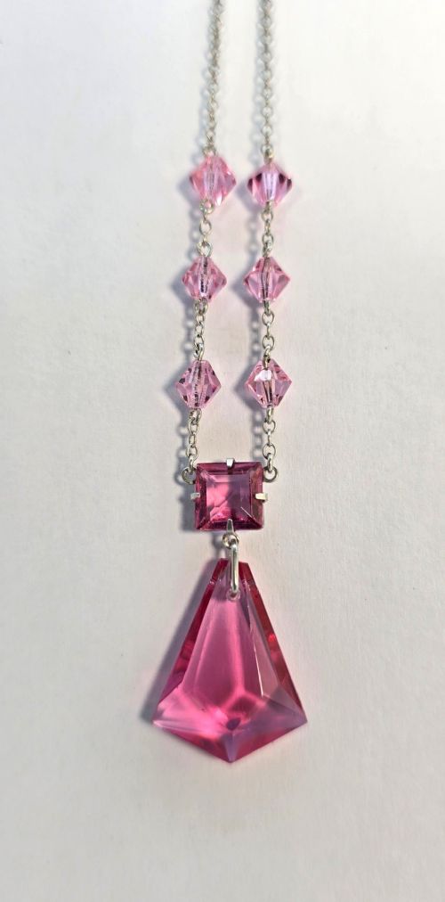 An Art Deco style silver chain necklace featuring faceted pink crystal bicone beads and a geometric triangular crystal pendant drop.