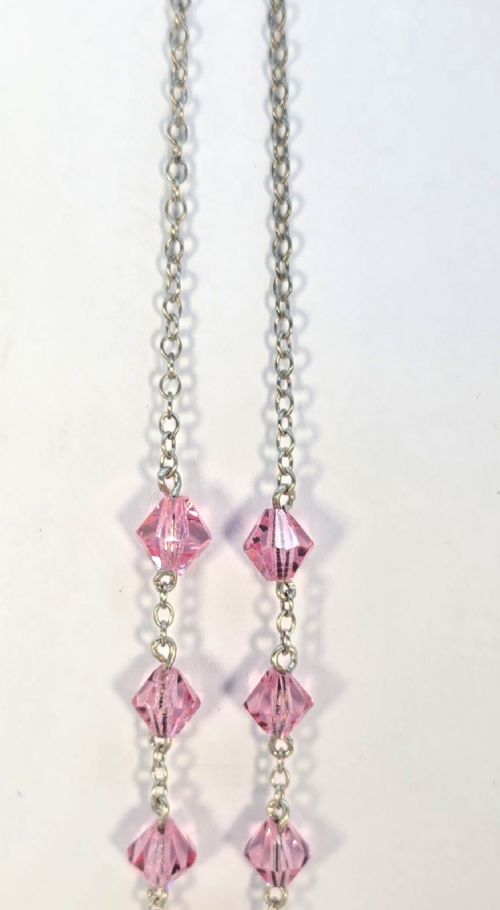 An Art Deco style silver chain necklace featuring faceted pink crystal bicone beads and a geometric triangular crystal pendant drop. View VI