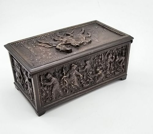 fig 1. A dark patinated bronze rectangular jewellery casket featuring raised relief scenes of horses on the lid and rural figures on the side, displayed with its key.
