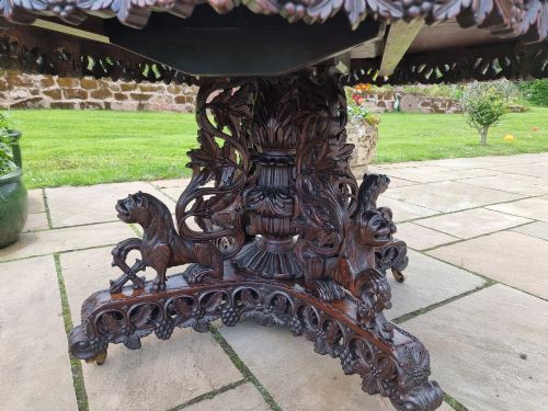 fig 3. A mid-19th century Anglo-Indian padauk centre table featuring a scalloped edge top, deeply carved pierced floral apron, and a central pedestal supported by carved lion figures on castors.