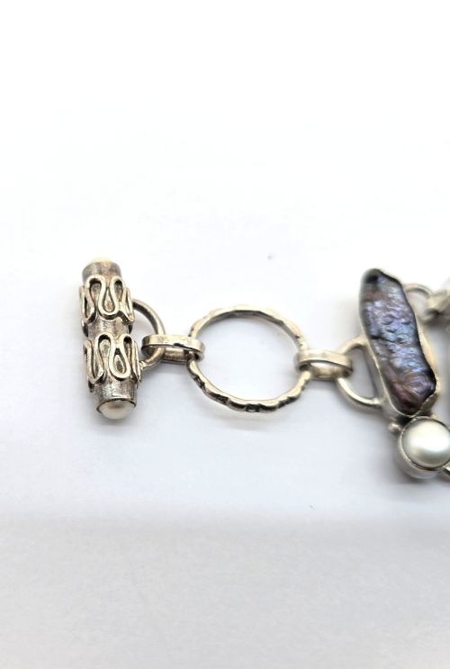 fig 4. A 1960s Japanese silver jewellery set featuring an articulated link bracelet and a matching ring set with elongated, iridescent Biwa pearls and round white pearls.