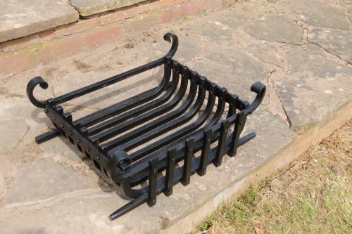fig 1. A black wrought iron fire basket featuring vertical slatted bars, hand-riveted joints, and scrolled corner handles.