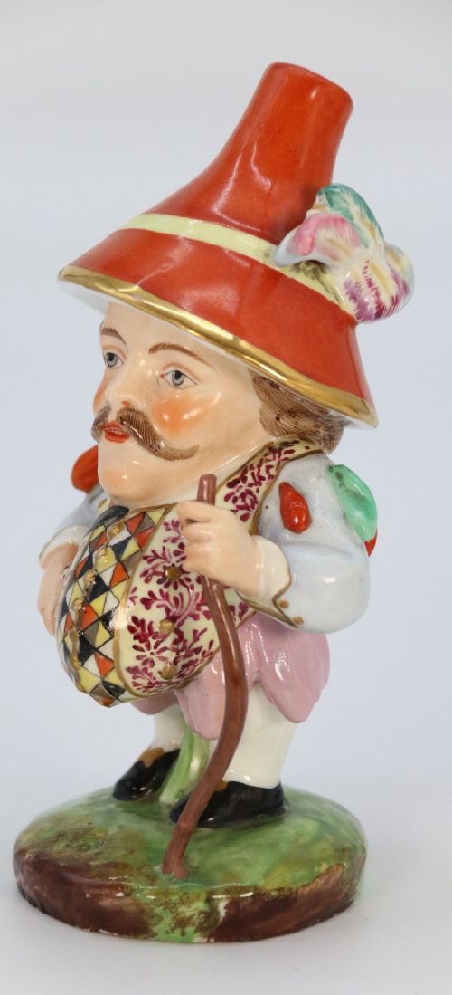 A pair of 19th-century polychrome Samson porcelain figures depicting dwarves wearing oversized brimmed hats and patterned waistcoats on mound bases. View X