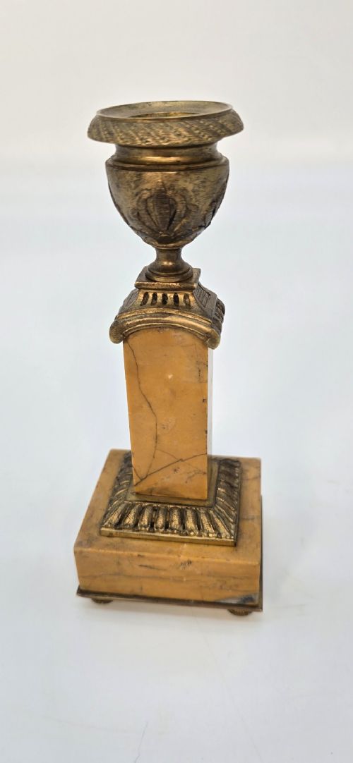 A pair of nineteenth-century French Empire gilt-bronze candlesticks featuring urn-shaped nozzles and applied bronze foliage on rectangular yellow marble bases. View V