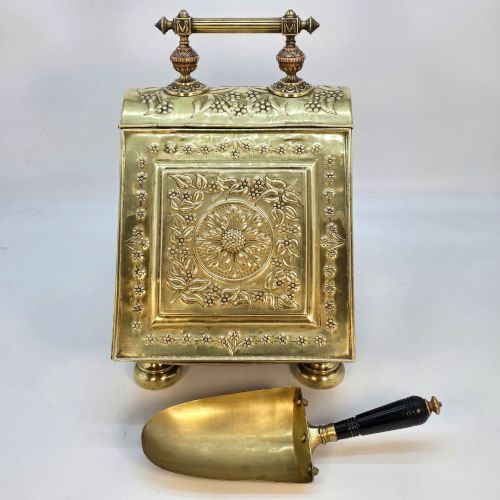 fig 1. Victorian sloped brass coal box featuring repousse sunflower motifs, turned brass feet, and a top carrying handle with an integrated rear shovel.