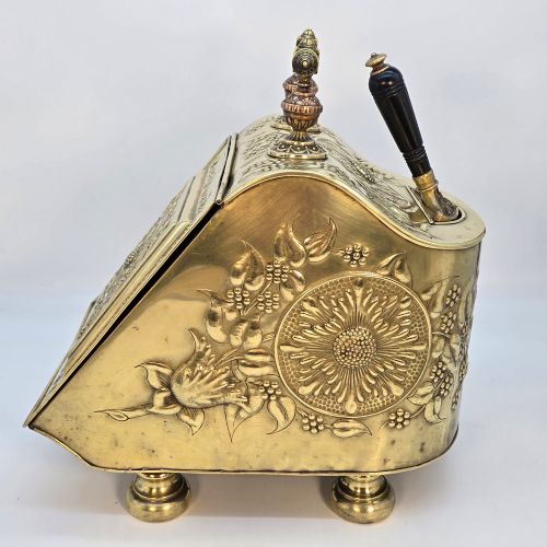 fig 3. Victorian sloped brass coal box featuring repousse sunflower motifs, turned brass feet, and a top carrying handle with an integrated rear shovel.