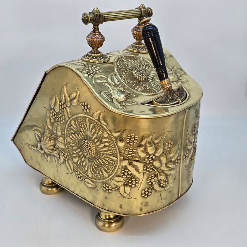 fig 4. Victorian sloped brass coal box featuring repousse sunflower motifs, turned brass feet, and a top carrying handle with an integrated rear shovel.