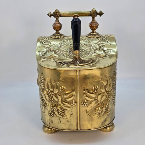 fig 5. Victorian sloped brass coal box featuring repousse sunflower motifs, turned brass feet, and a top carrying handle with an integrated rear shovel.