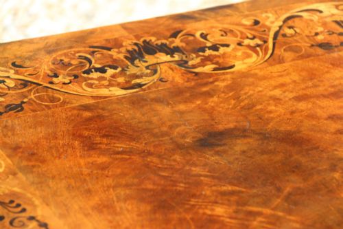 fig 1. An early 19th-century flame mahogany library table featuring floral marquetry inlays around the rectangular top, frieze drawers with brass handles, and carved trestle supports.