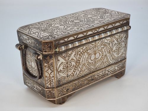 fig 2. A rectangular dark bronze betel box embellished with detailed silver floral scrollwork inlay and featuring side handles.