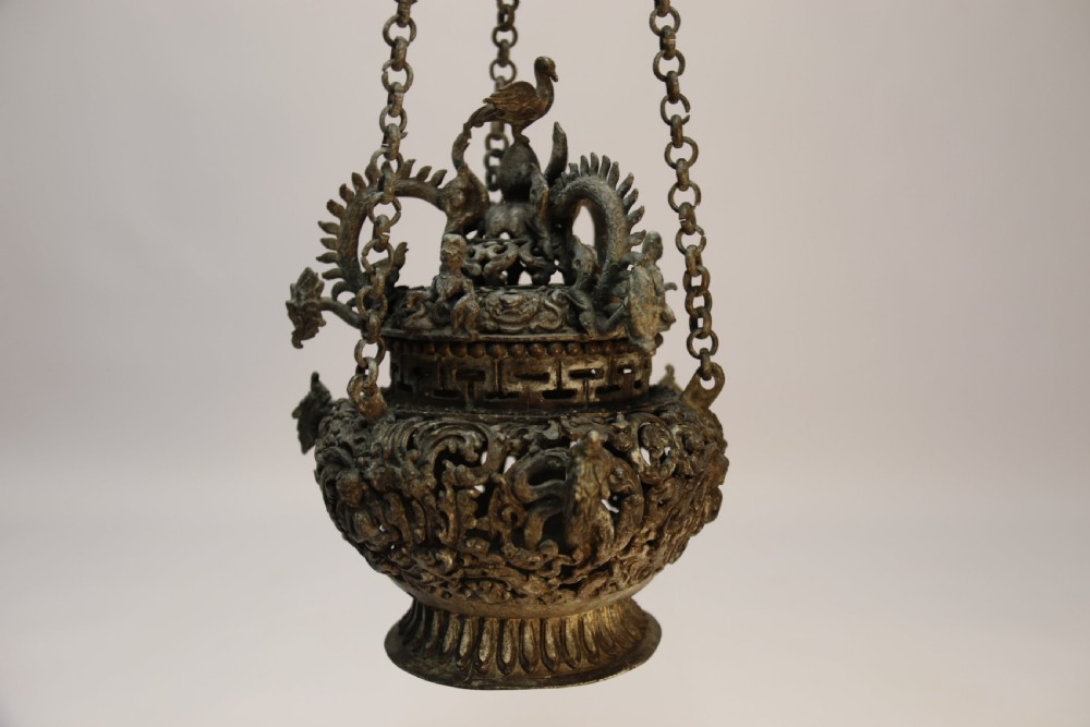A dark patinated bronze hanging incense burner featuring dragon openwork motifs and a bird finial suspended by three link chains. View II
