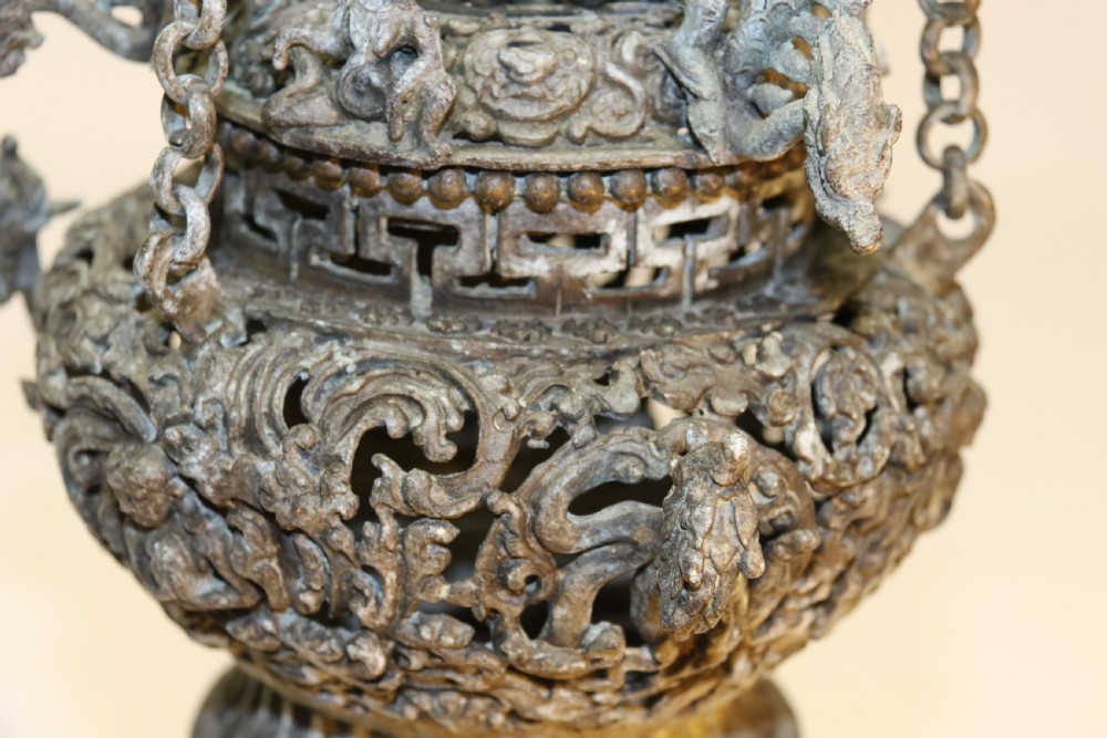 A dark patinated bronze hanging incense burner featuring dragon openwork motifs and a bird finial suspended by three link chains. View IV
